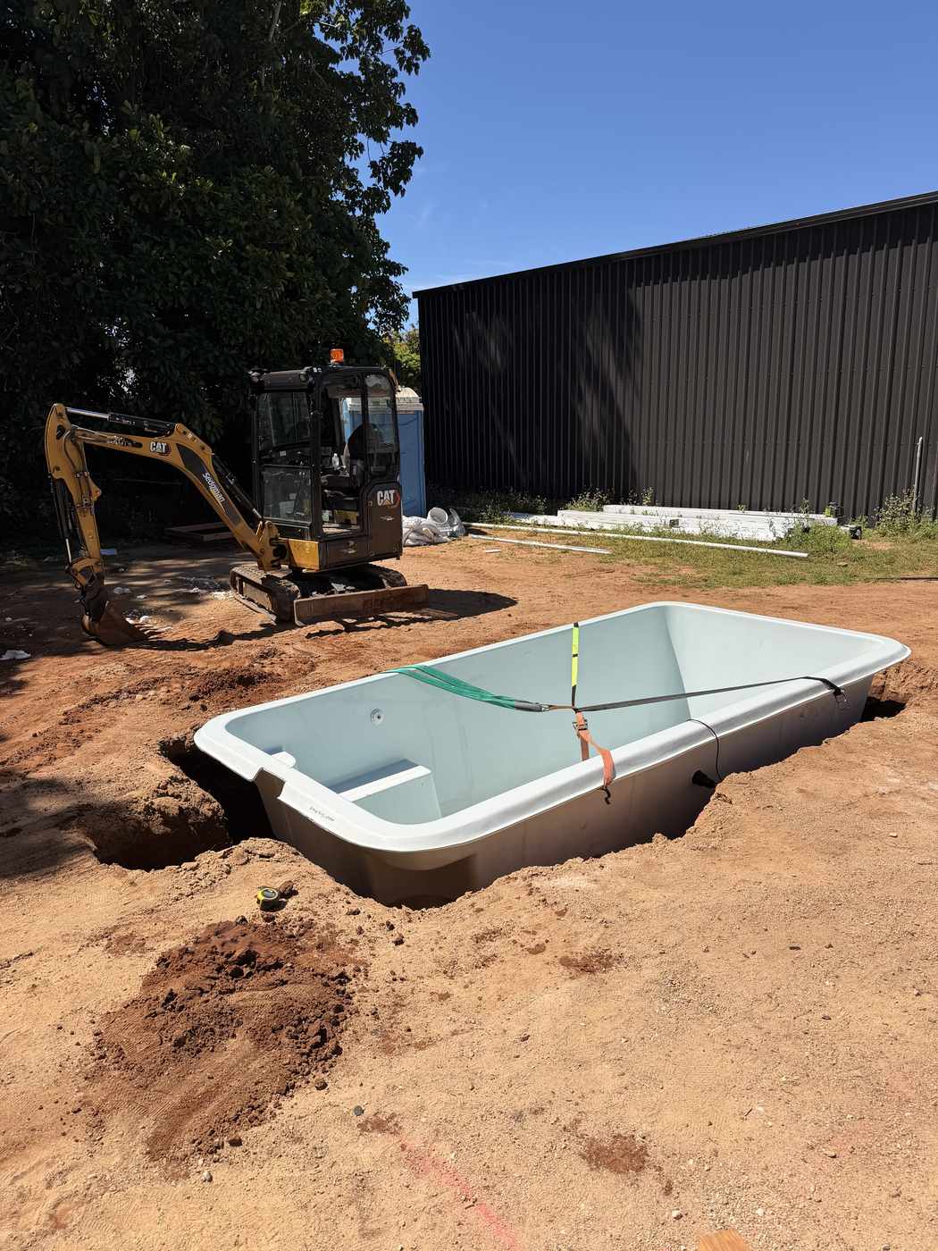 Cleo fibreglass pool shell beside the excavator on delivery day, Mission Beach