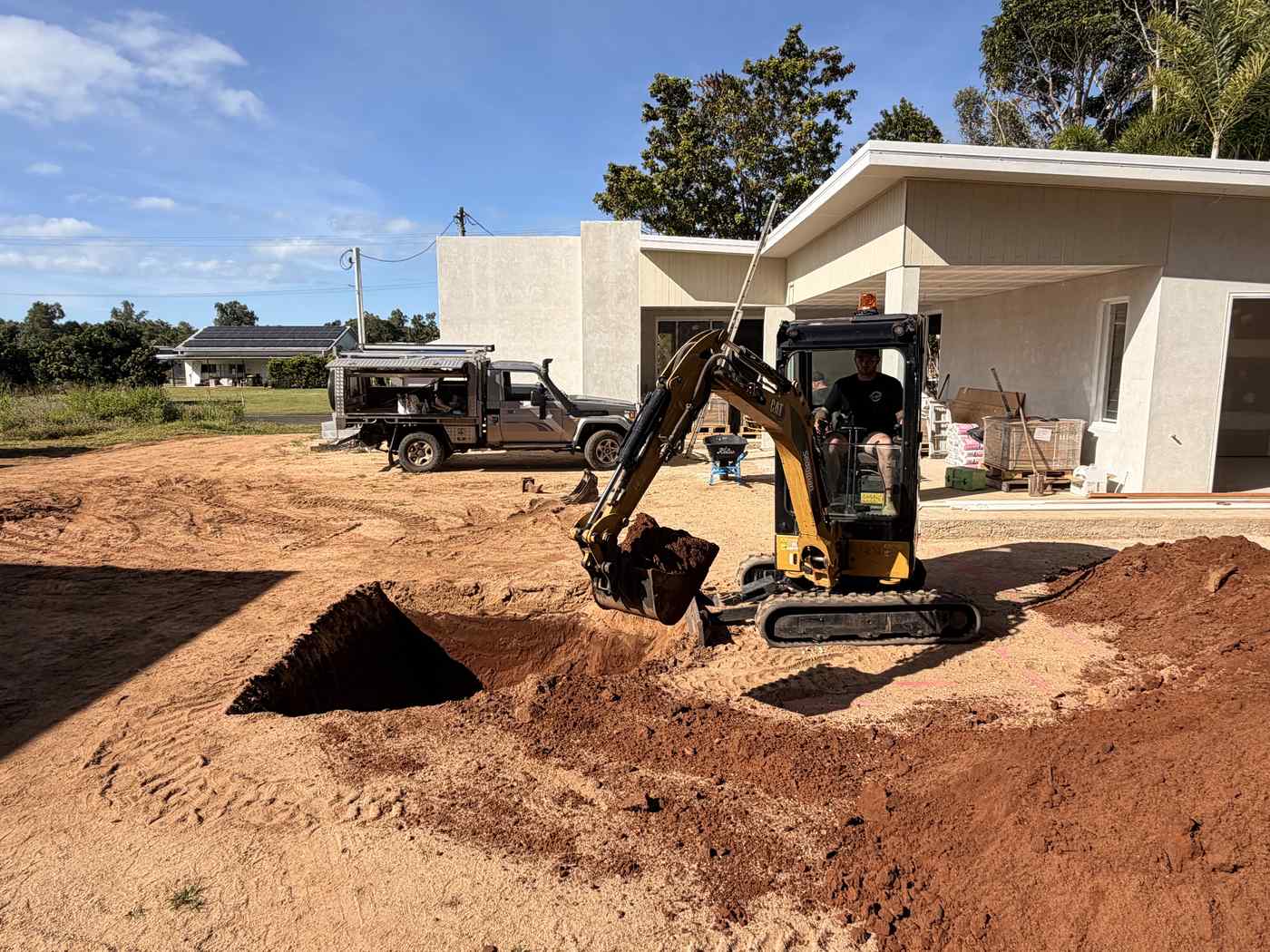 Excavator digging the pool site with the house behind, Mission Beach