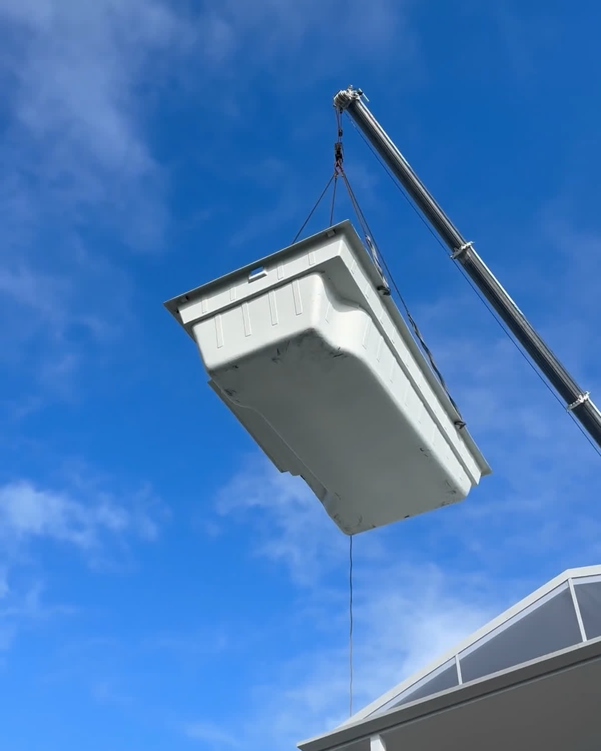 A Hull Pools fibreglass shell being craned into a backyard